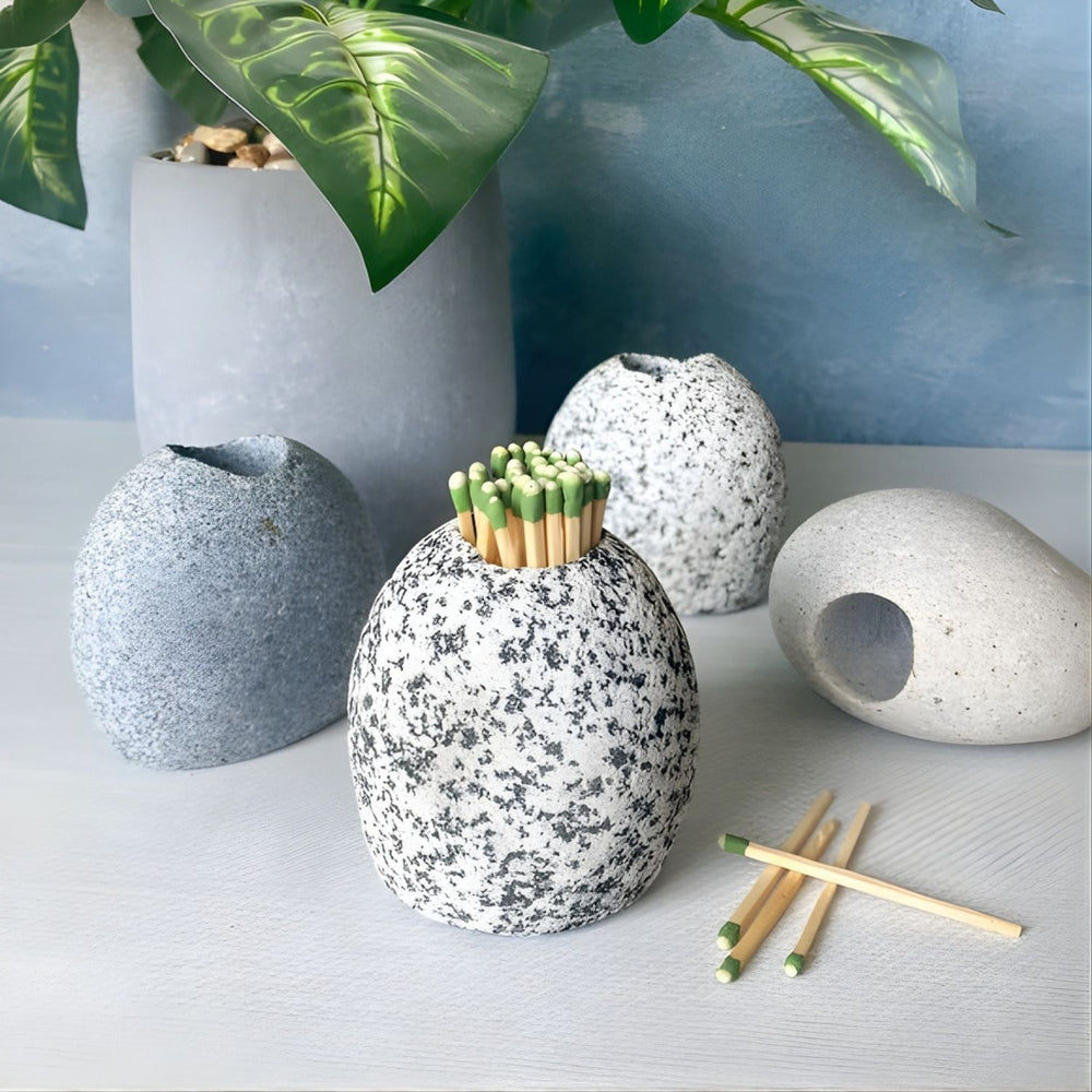 A single, round, gray speckled stone holder standing on a white surface, filled with a bundle of strike anywhere matchsticks.
