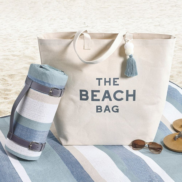 Beach stripe picnic blanket styled with beach bag on sand