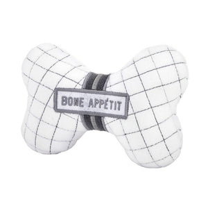 Angled view of bone-shaped plush dog toy with embroidered “Bone Appétit” text and squeaker