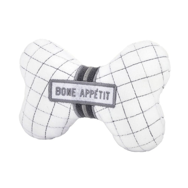 Angled view of bone-shaped plush dog toy with embroidered “Bone Appétit” text and squeaker