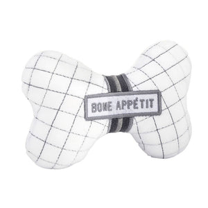 Angled view of bone-shaped plush dog toy with embroidered “Bone Appétit” text and squeaker