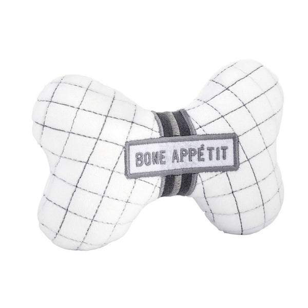 Angled view of bone-shaped plush dog toy with embroidered “Bone Appétit” text and squeaker