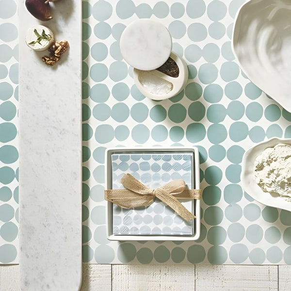 Ceramic napkin tray with blue dot paper napkins styled on coastal table with oyster bowls and marble serving board.