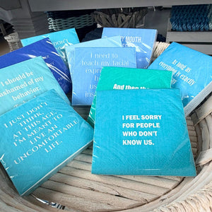 Blue and teal cocktail napkins with funny sayings on display 