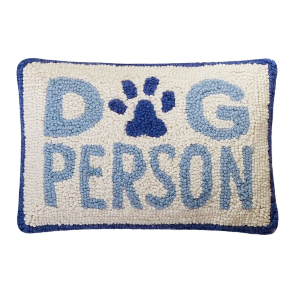 Rectangular hand-hooked wool pillow with "DOG PERSON" in blue text and a paw print motif on a cream background with a navy border