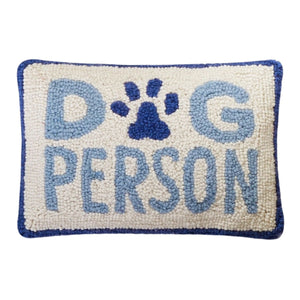 Rectangular hand-hooked wool pillow with "DOG PERSON" in blue text and a paw print motif on a cream background with a navy border