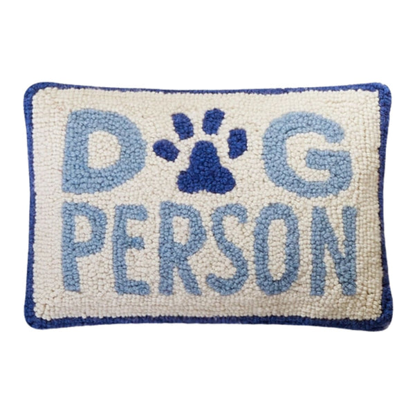 Rectangular hand-hooked wool pillow with "DOG PERSON" in blue text and a paw print motif on a cream background with a navy border