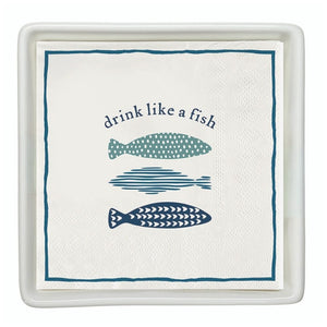 Cocktail napkins with “Drink Like a Fish” fish design placed in a white ceramic napkin tray