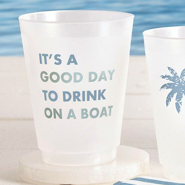 Frosted reusable cups with “It’s a Good Day to Drink on a Boat” text and palm tree design by the water