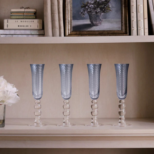 Handcrafted blue champagne flutes with ripple-like swirl optics, inspired by ocean movement and light.