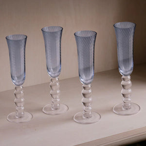 Set of four blue swirl champagne glasses catching light like water, ideal for coastal and nautical décor.
