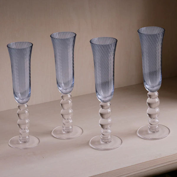 Set of four blue swirl champagne glasses catching light like water, ideal for coastal and nautical décor.