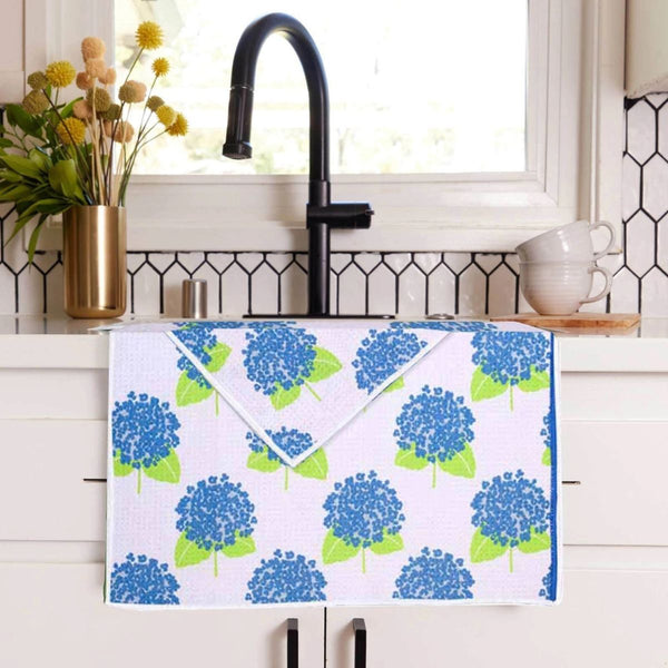 Coastal sustainable microfiber tea towel with blue hydrangea print on white background hanging on kitchen sink