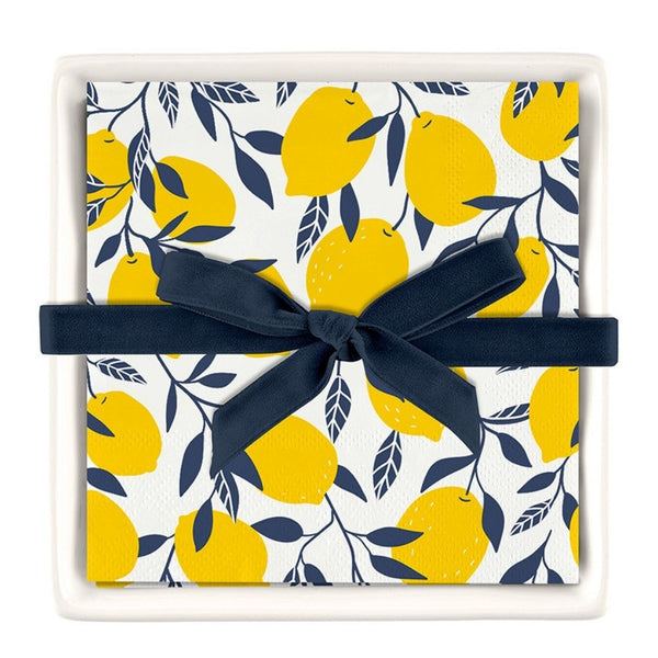 Lemon print cocktail napkins displayed in a white ceramic napkin tray with ribbon