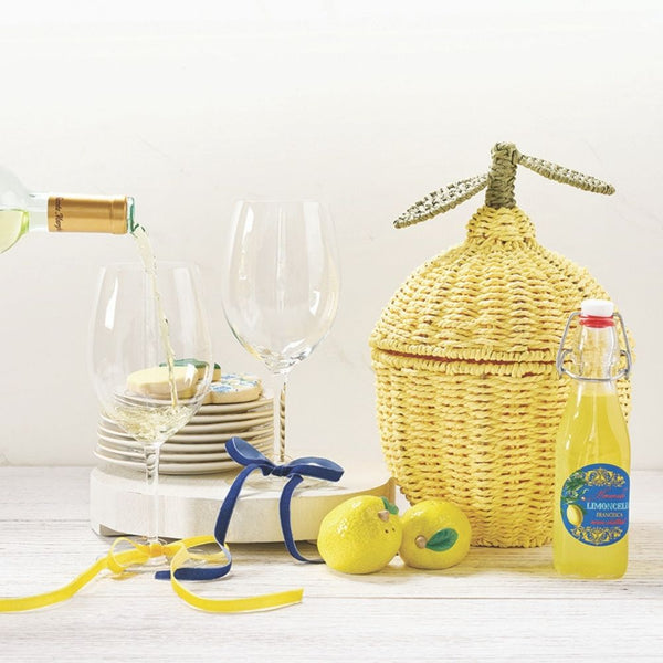 Lemon shaped wicker basket with metal leaf detail styled with wine glasses and lemons