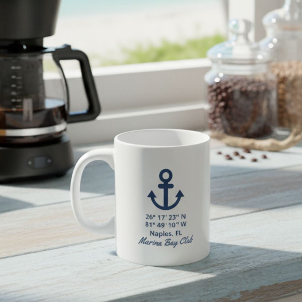 White ceramic mug with blue anchor design and personalized latitude and longitude coordinates.