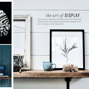 Decorative shelf with framed artwork, cup, and shell on a white wall with text about displaying items.