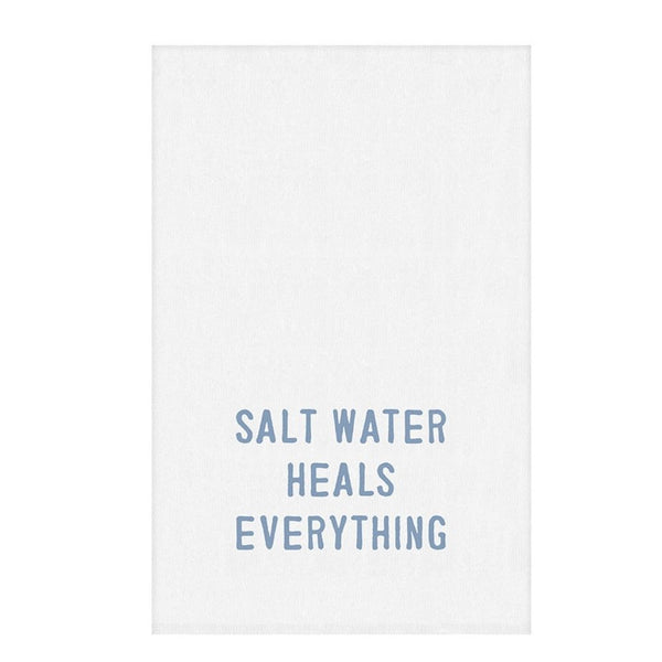 Flat lay of white cotton towel with coastal blue “Salt Water Heals Everything” lettering