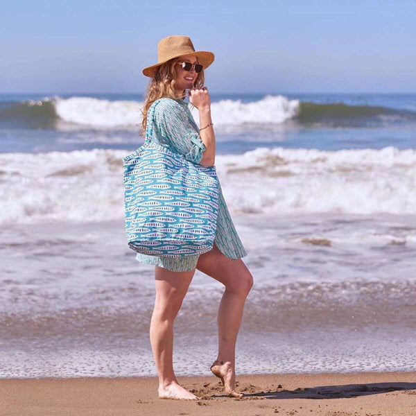 Large coastal-inspired tote made from durable cotton canvas, featuring self-fabric handles, inside zipper pocket, and magnetic snap for versatile use