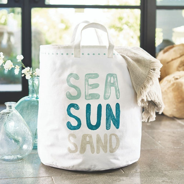 Large cotton canvas tote bag with Sea Sun Sand lettering styled with coastal decor and glass vases