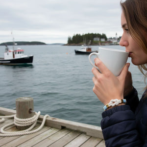 Slip-on coastal rope bracelet with wrapped thread and gold accents.