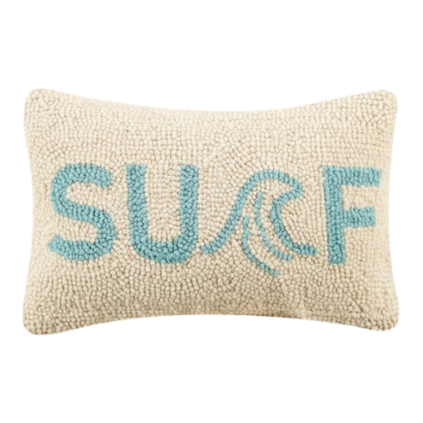 A rectangular 8x12 hooked wool pillow with "SURF" written in aqua blue text; the letter "R" features a stylized ocean wave design.