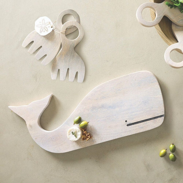 White mango wood whale-shaped serving board, 17.5 inches long, set on table, paired with wood servers
