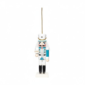 White and aqua coastal nutcracker ornament with hanging loop, featuring a round accessory, perfect for coastal living holiday décor.