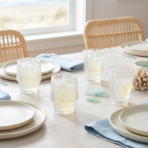 Iridescent Fish Drinking Glasses Displayed With Neutral Dinnerware and Blue Linen Napkins on a Coastal Dining Table